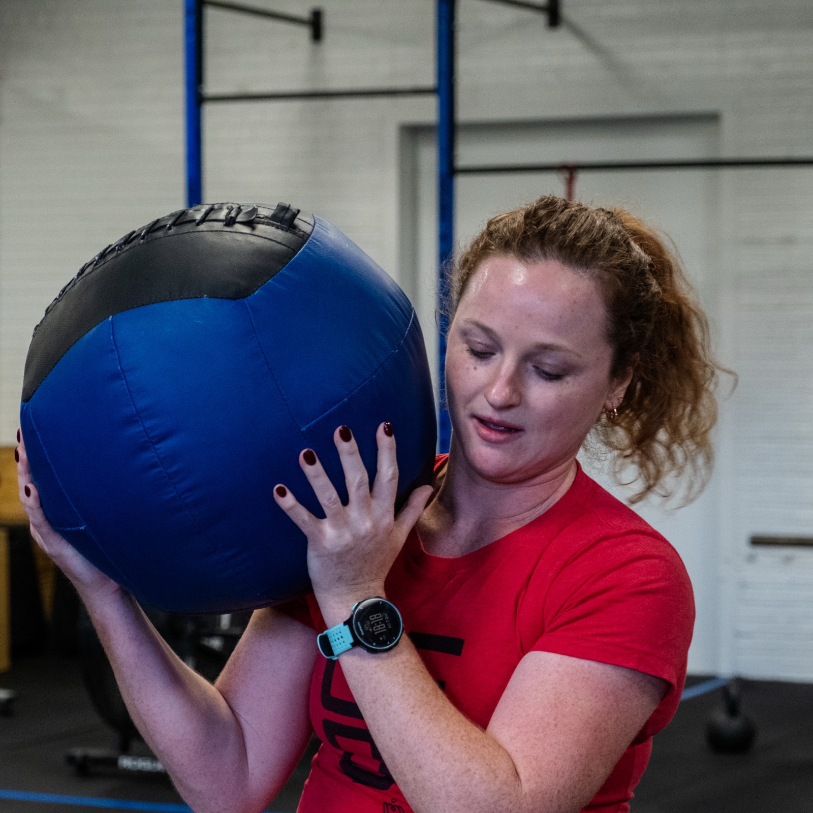 A coach correcting a member's position on a wall ball