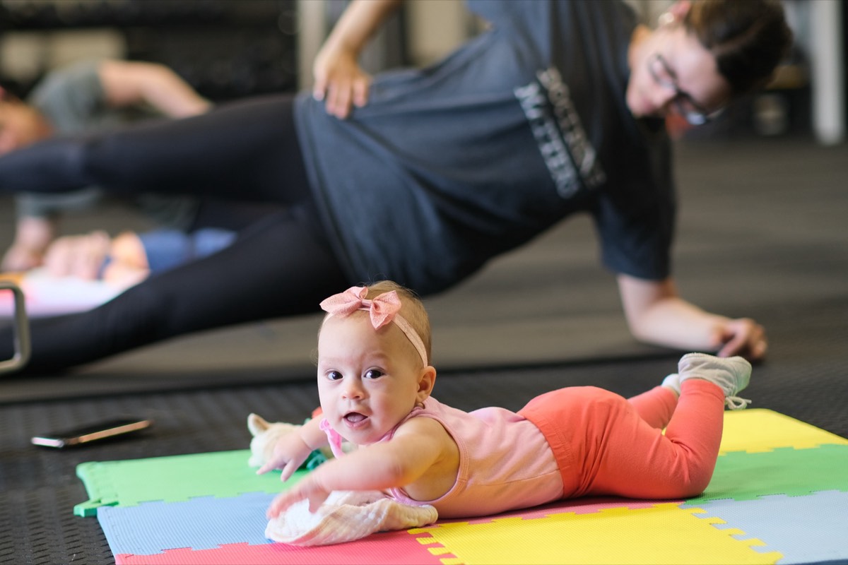 A mom working through the core exercises with her baby beside her