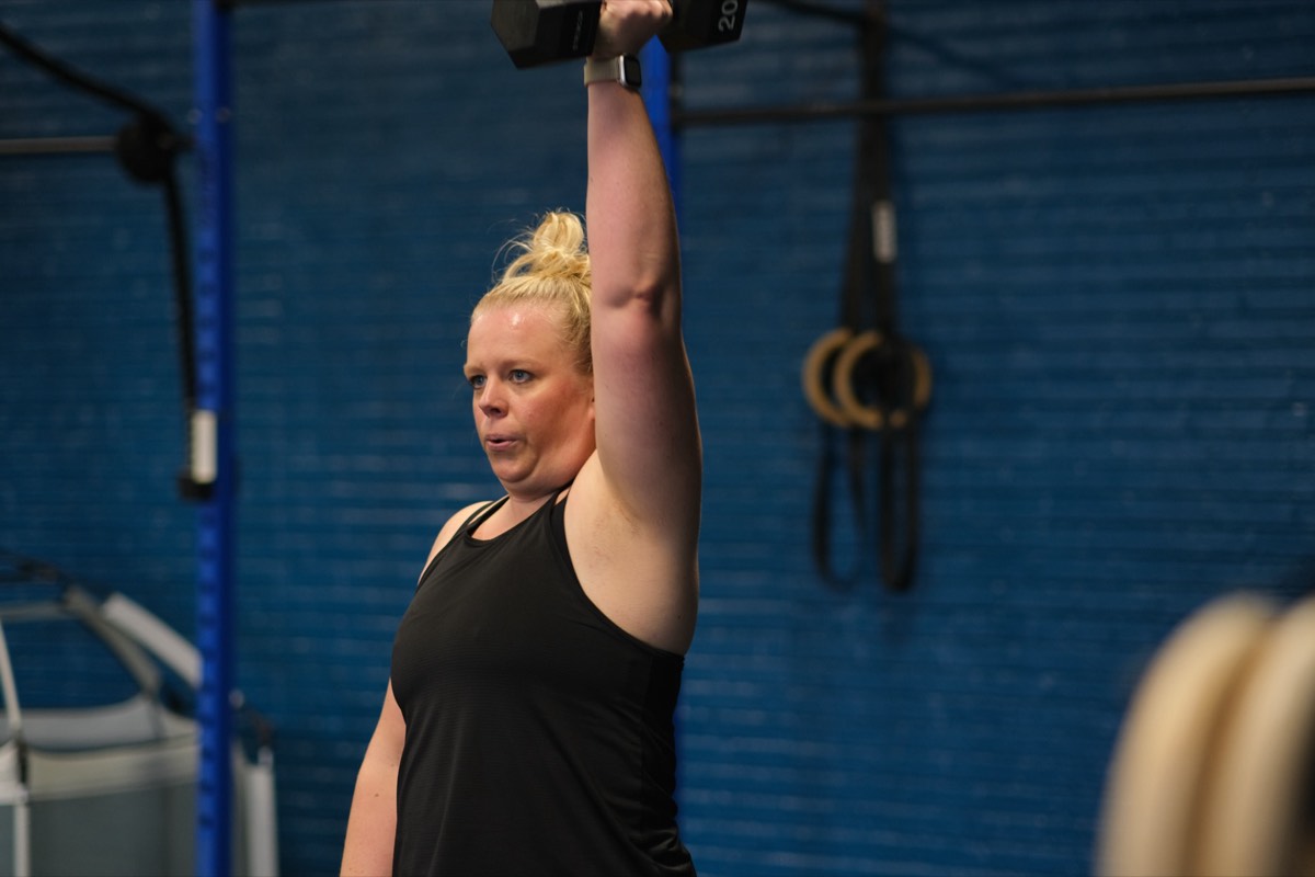 A mom pressing a kettlebell overhead